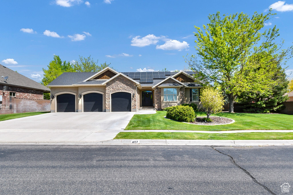 View of front of home with solar panels, a front yard, driveway, and stone siding