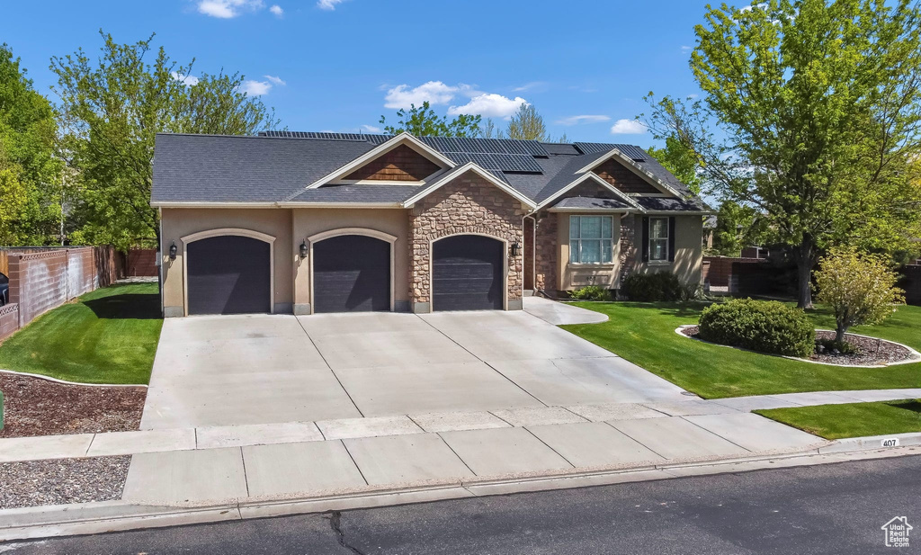 View of front of house featuring an attached garage, roof mounted solar panels, driveway, stone siding, and roof with shingles