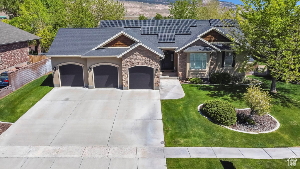 View of front of property with an attached garage, stone siding, concrete driveway, solar panels, and a shingled roof