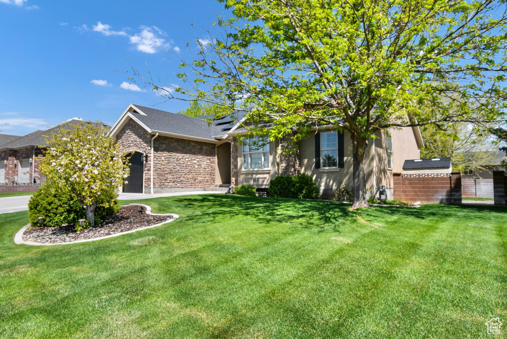 View of front of property with a front lawn, stone siding, and solar panels