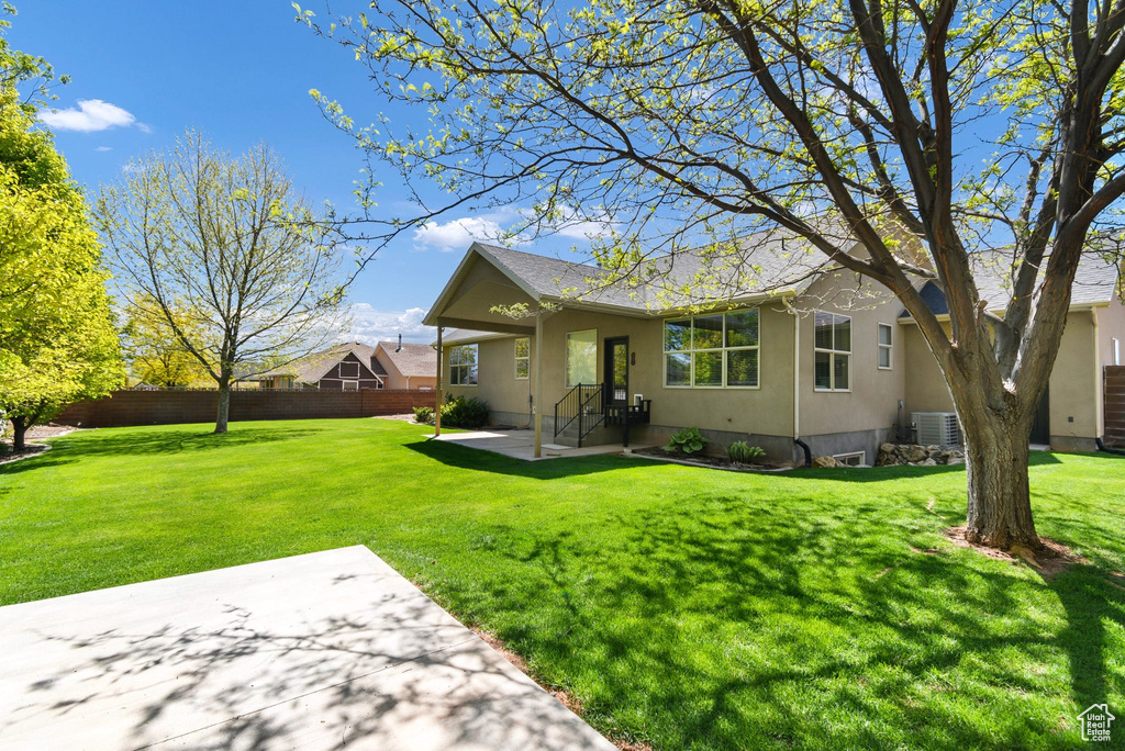 Rear view of house with a patio area, central AC, roof with shingles, and stucco siding