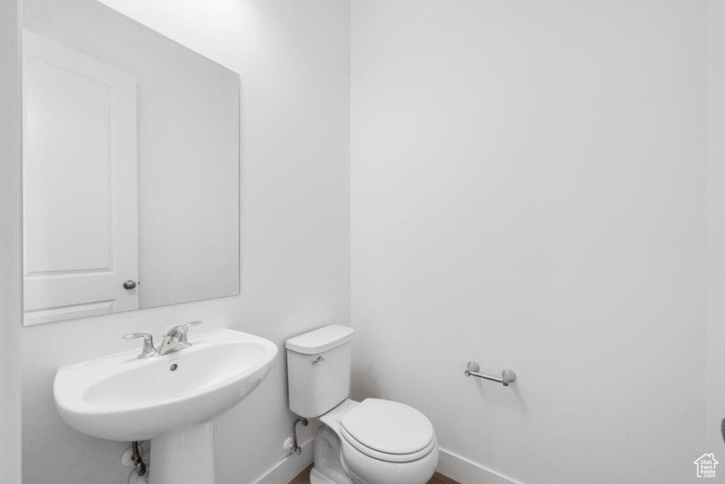 Half bath featuring a sink, baseboards, and toilet