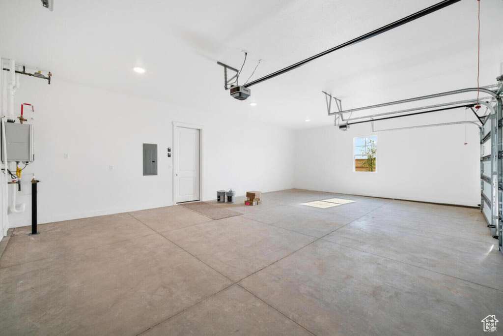 Garage with electric panel, a garage door opener, and water heater