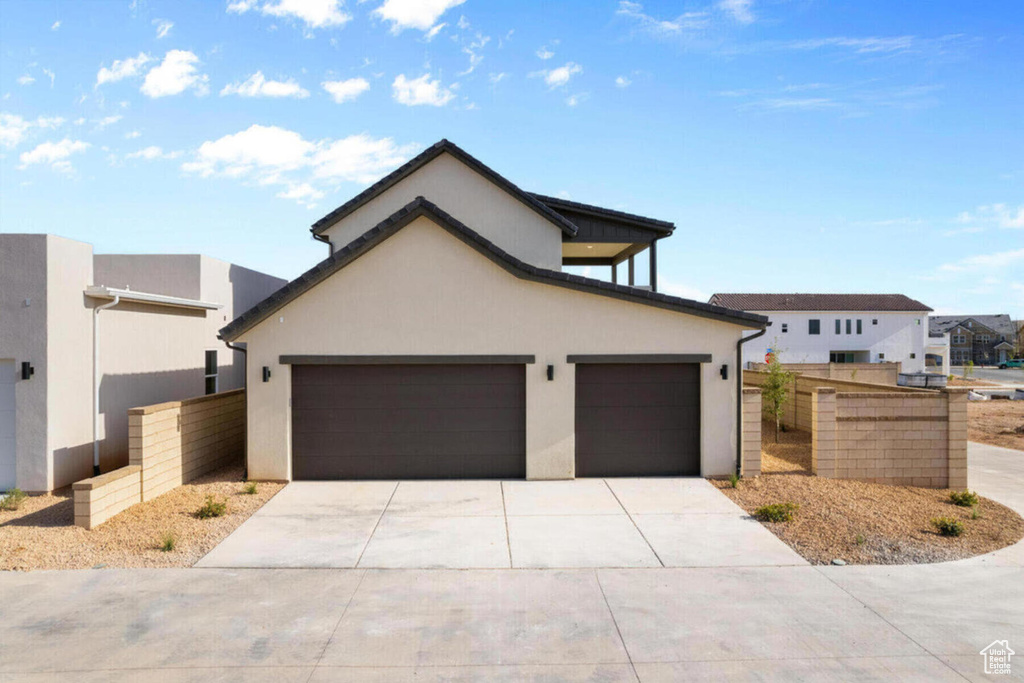 View of front of home featuring fence, a garage, driveway, and stucco siding