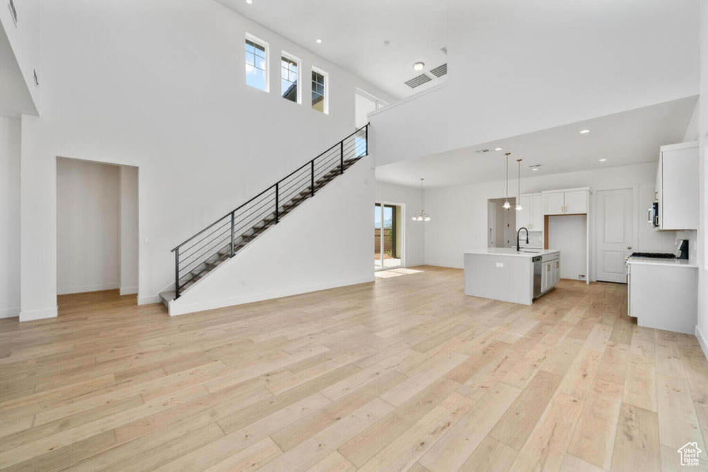 Unfurnished living room featuring stairway, visible vents, light wood-style flooring, recessed lighting, and a sink