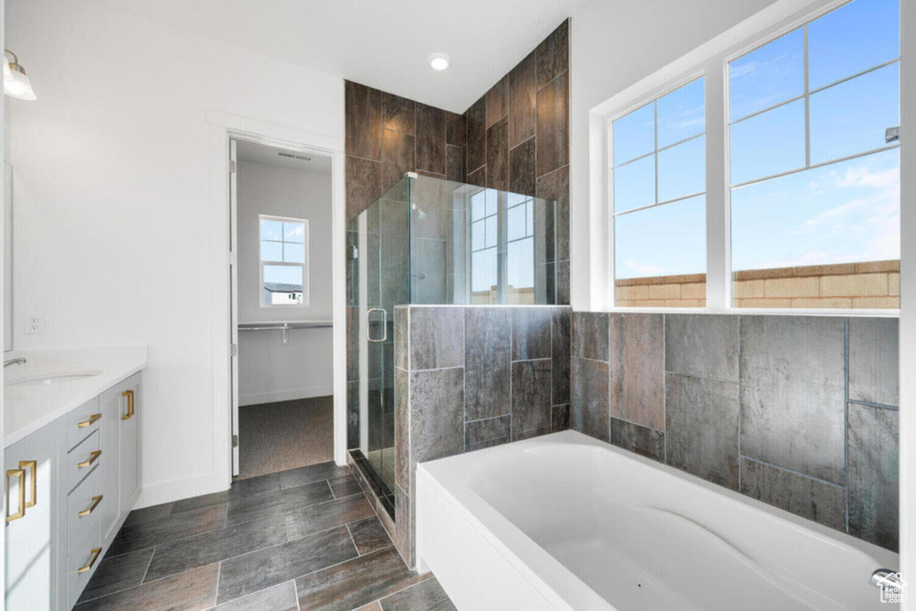 Bathroom with vanity, baseboards, wood tiled floor, a stall shower, and a garden tub