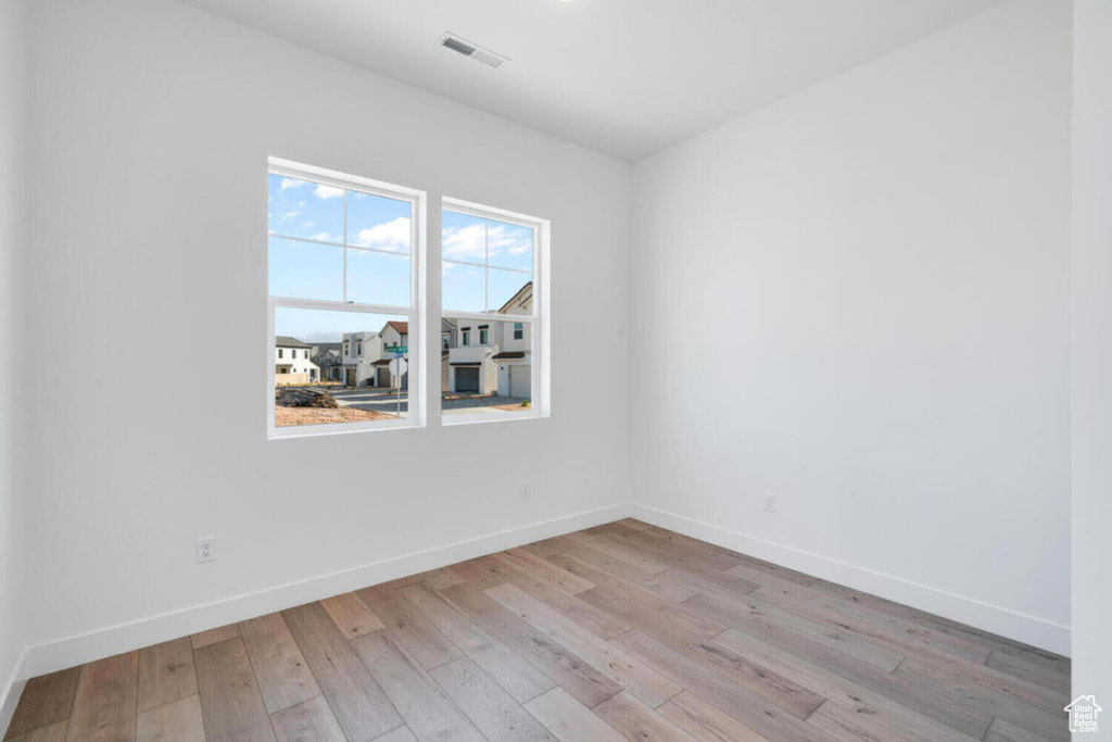 Spare room with hardwood / wood-style flooring, baseboards, and visible vents