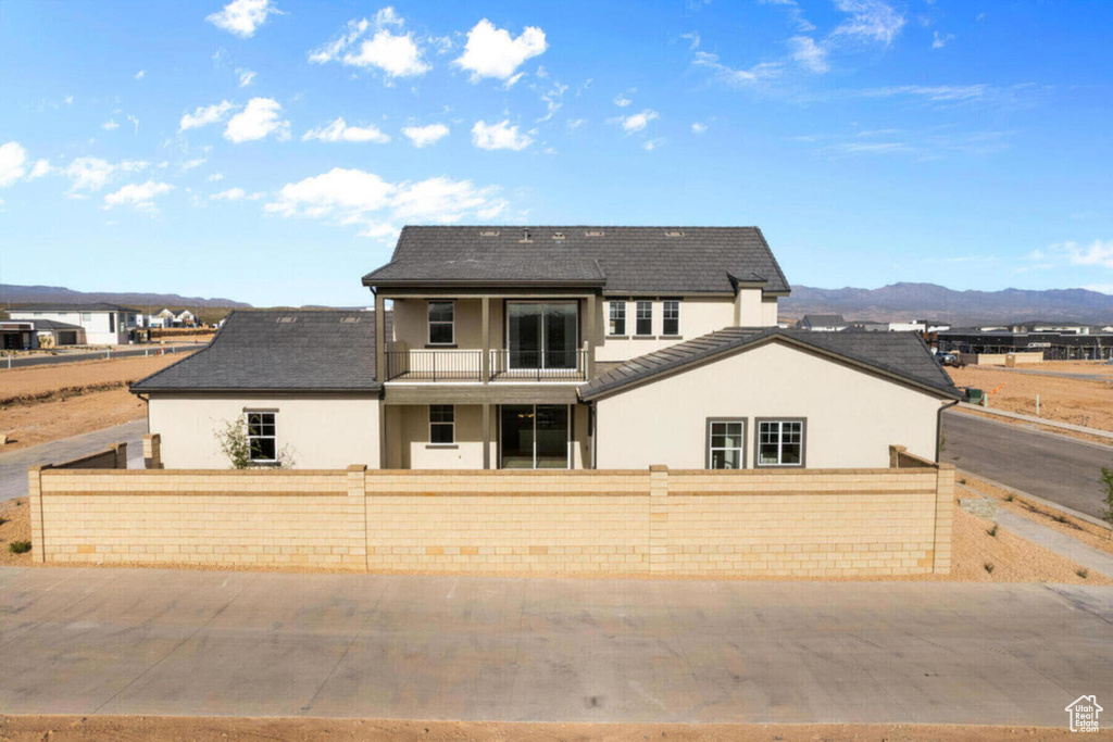 View of front of house featuring a balcony, a fenced front yard, and stucco siding