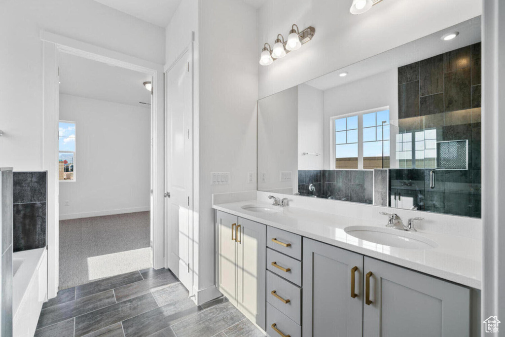 Bathroom featuring a sink, a wealth of natural light, double vanity, and a tub