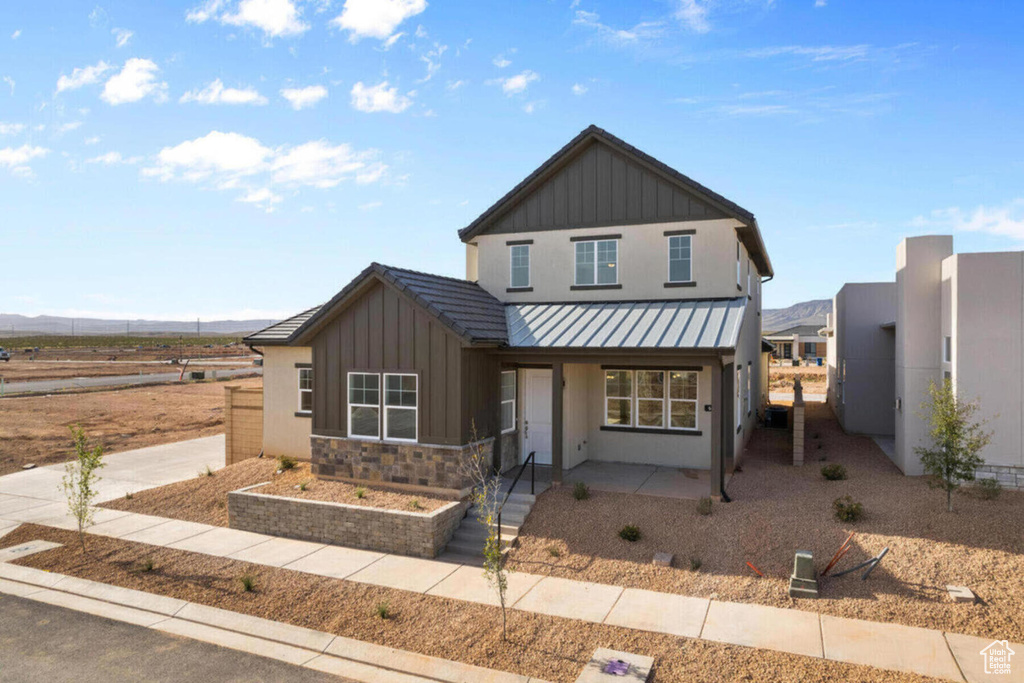 View of front facade with fence, a standing seam roof, stone siding, board and batten siding, and metal roof