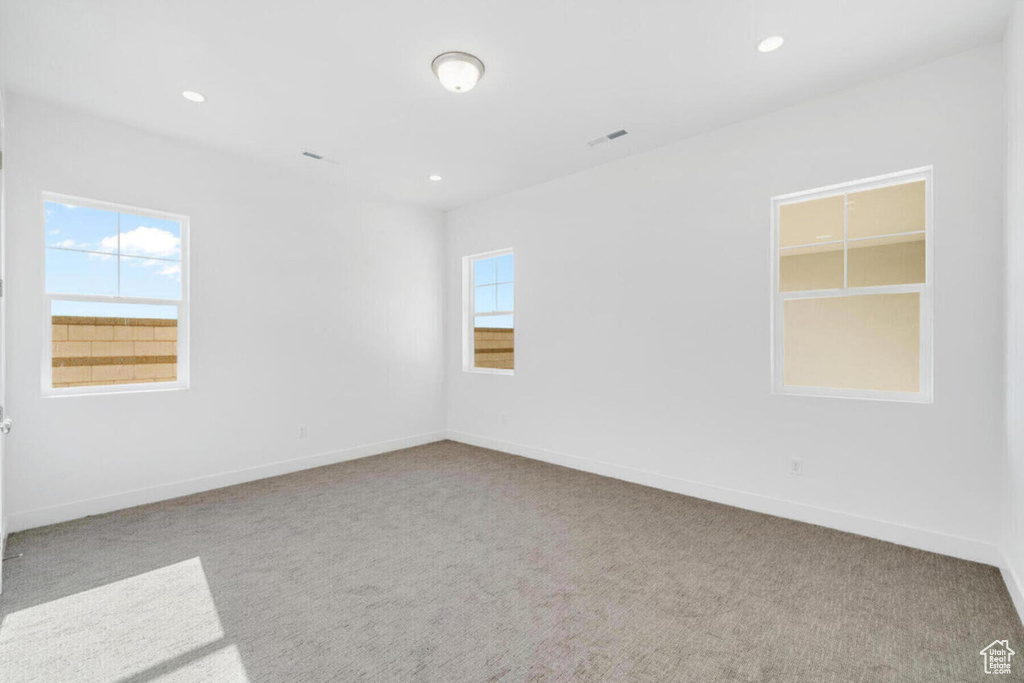 Carpeted spare room featuring recessed lighting, baseboards, and plenty of natural light