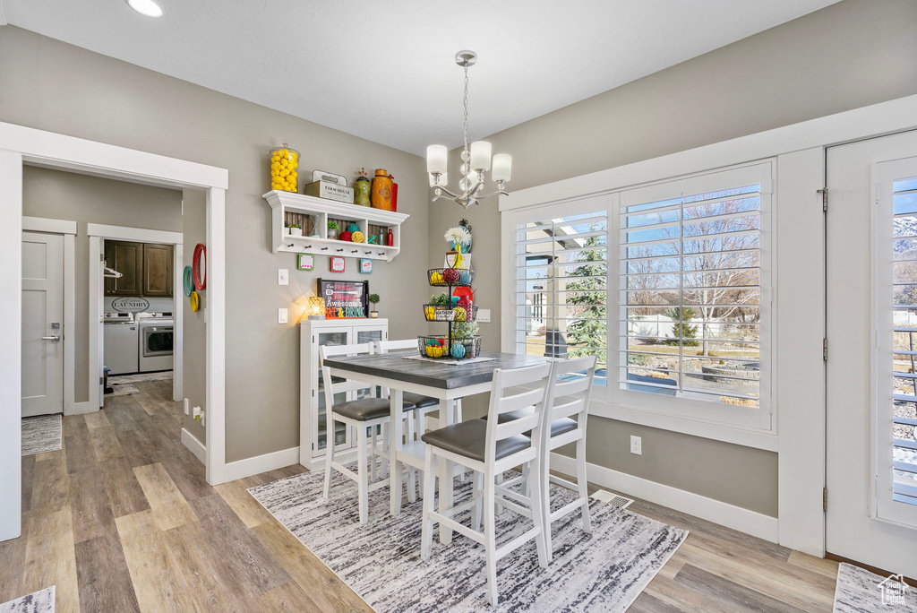 Dining area with baseboards, a notable chandelier, independent washer and dryer, and light wood finished floors