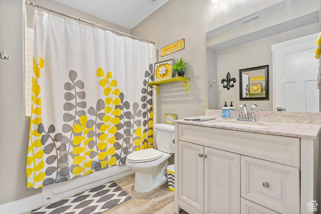 Bathroom with visible vents, toilet, vanity, and shower / tub combo with curtain