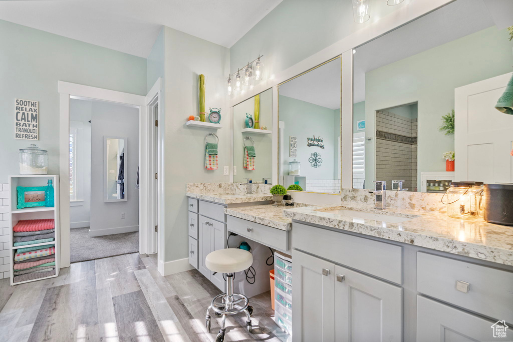 Full bath with vanity, baseboards, and wood finished floors