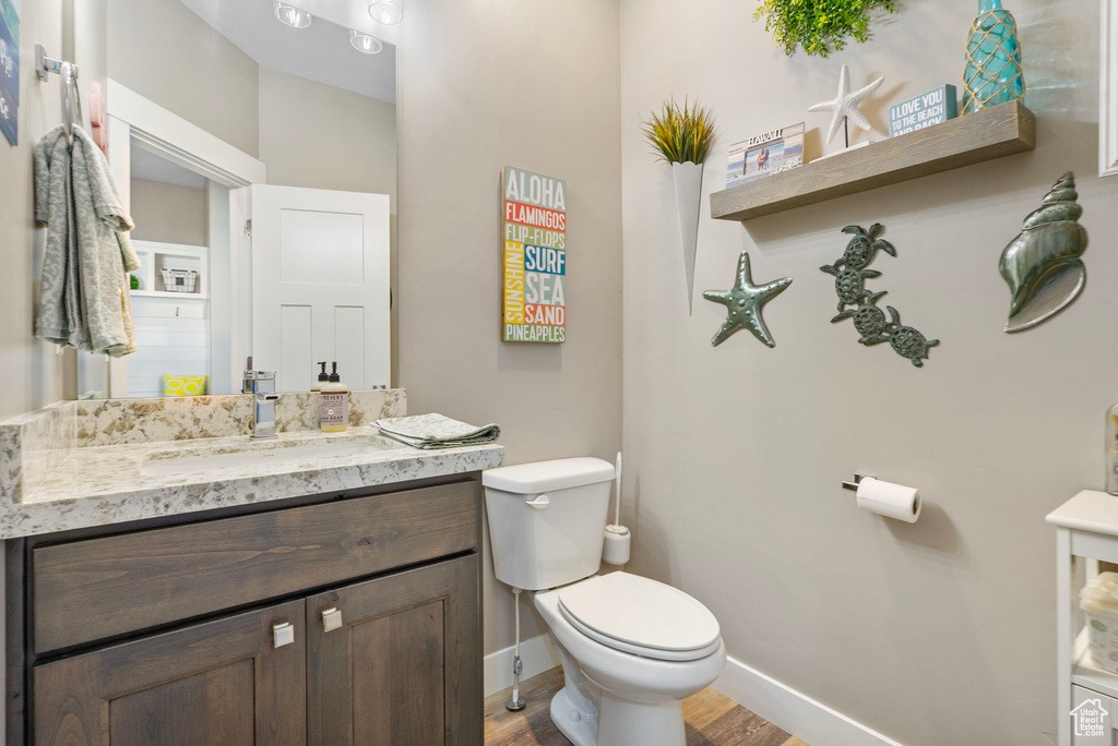 Bathroom with toilet, vanity, baseboards, and wood finished floors