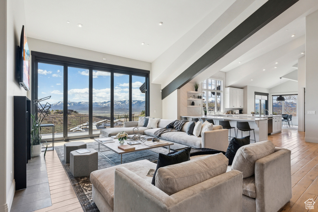 Living area with recessed lighting, baseboards, light wood finished floors, and lofted ceiling
