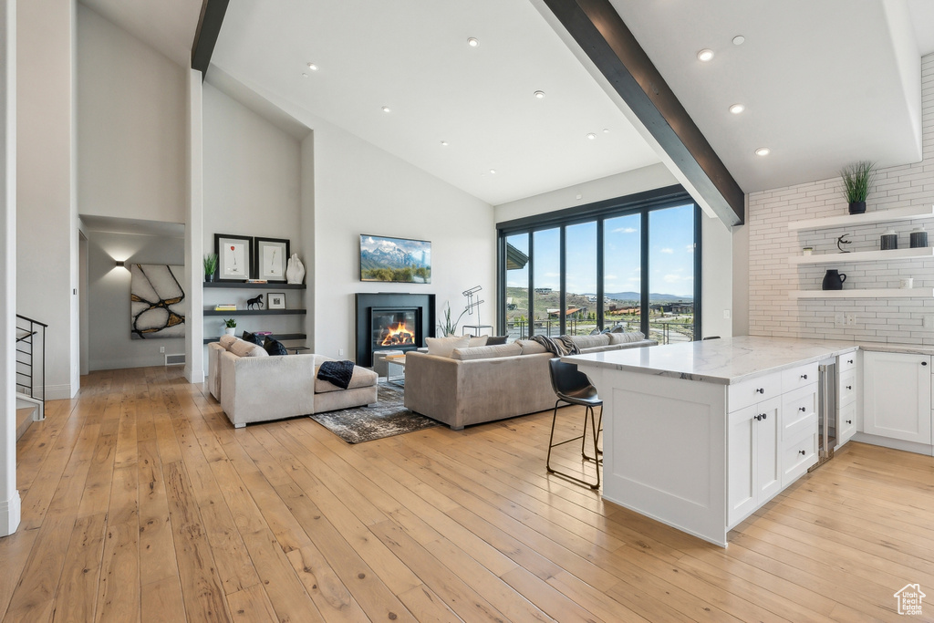 Kitchen featuring white cabinets, light stone counters, a kitchen breakfast bar, a glass covered fireplace, and a peninsula
