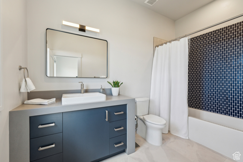 Full bathroom featuring vanity, shower / bath combo, and toilet
