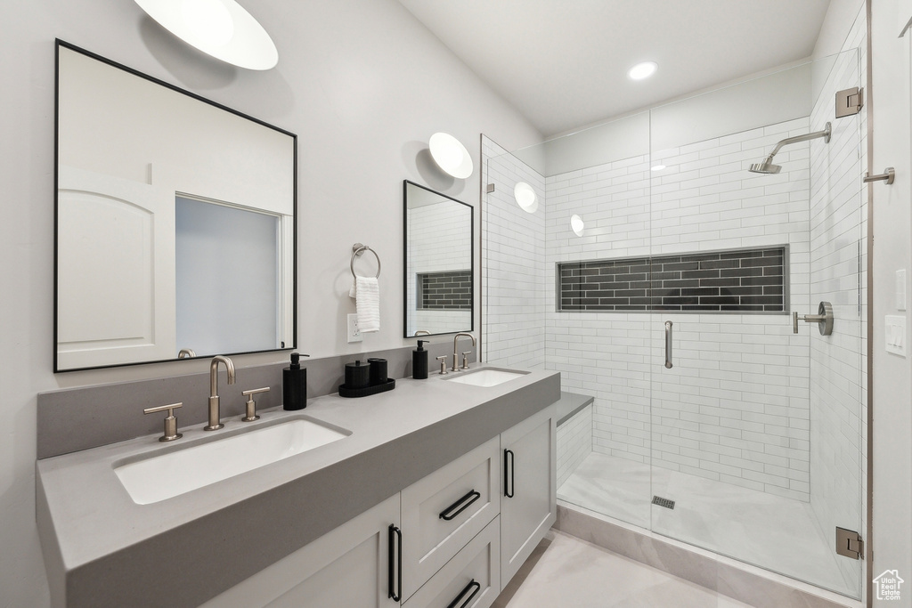 Bathroom with a sink, a shower stall, recessed lighting, and double vanity