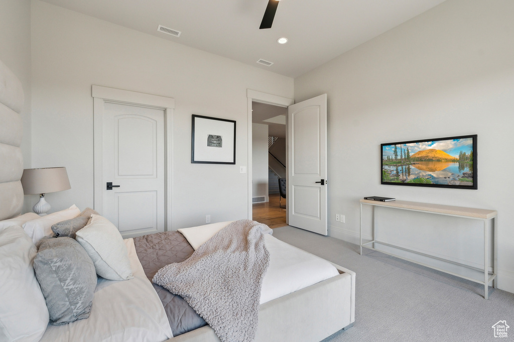 Living area with a ceiling fan, light colored carpet, visible vents, and baseboards