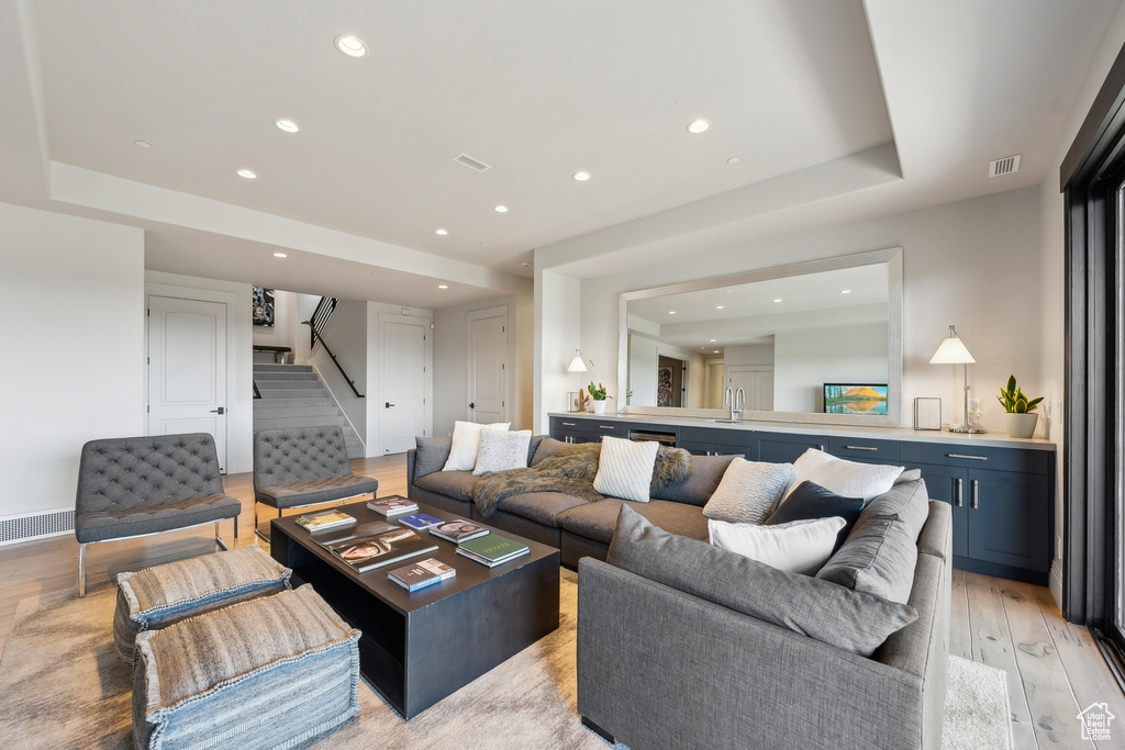 Living room featuring stairs, light wood-style flooring, and visible vents