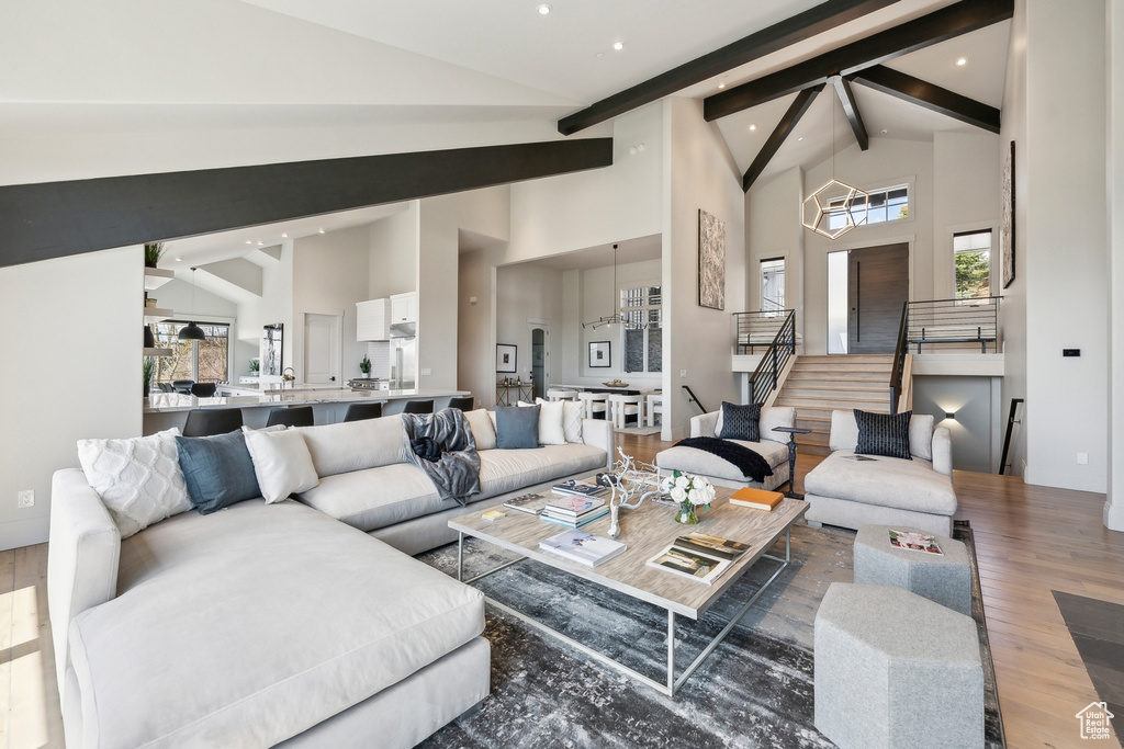 Living area featuring stairs, high vaulted ceiling, a healthy amount of sunlight, and wood finished floors