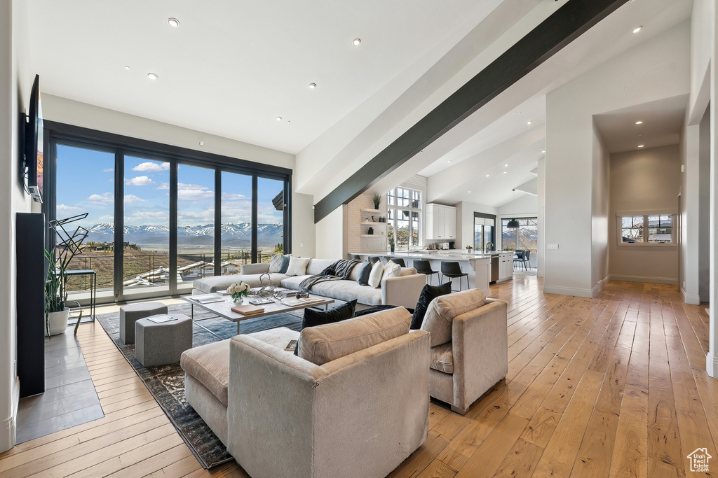 Living room featuring vaulted ceiling, light wood-type flooring, baseboards, a mountain view, and recessed lighting