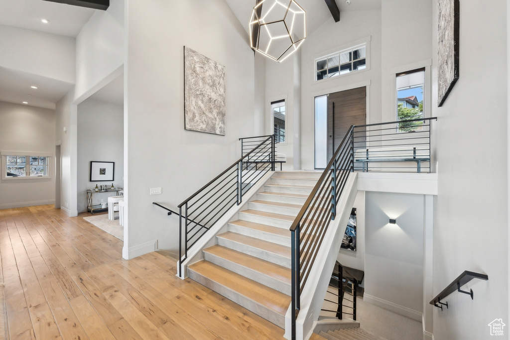 Stairway featuring beamed ceiling, high vaulted ceiling, baseboards, and wood-type flooring