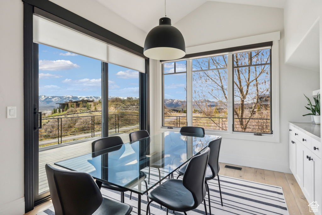 Dining area with visible vents, baseboards, a mountain view, light wood finished floors, and vaulted ceiling