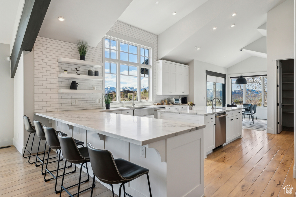 Kitchen with open shelves, a sink, white cabinetry, and a kitchen breakfast bar