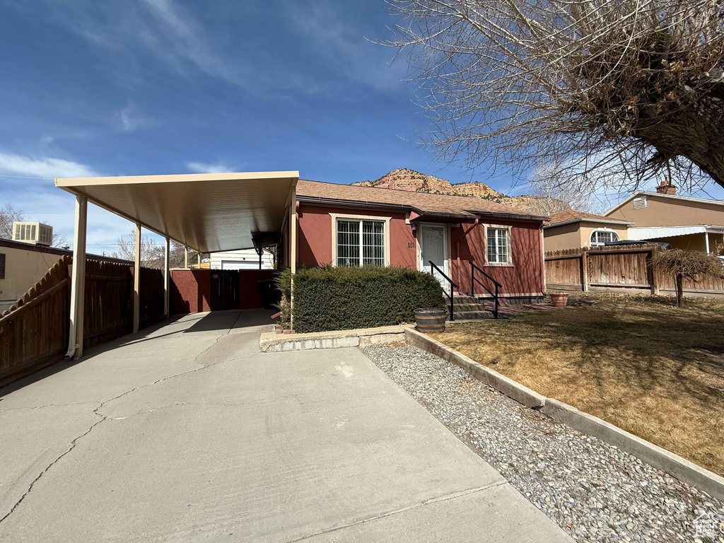 View of front facade with a carport, driveway, and fence