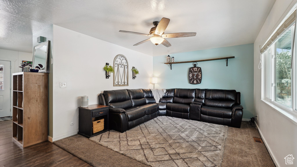 Living room with baseboards, a textured ceiling, wood finished floors, and a ceiling fan