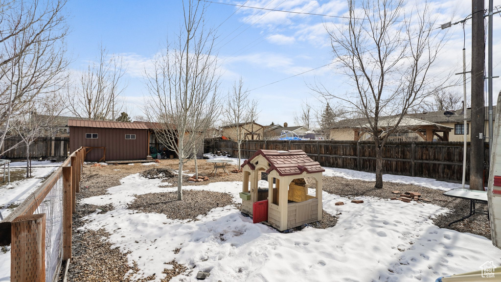Yard layered in snow featuring an outbuilding, a fenced backyard, and a storage shed