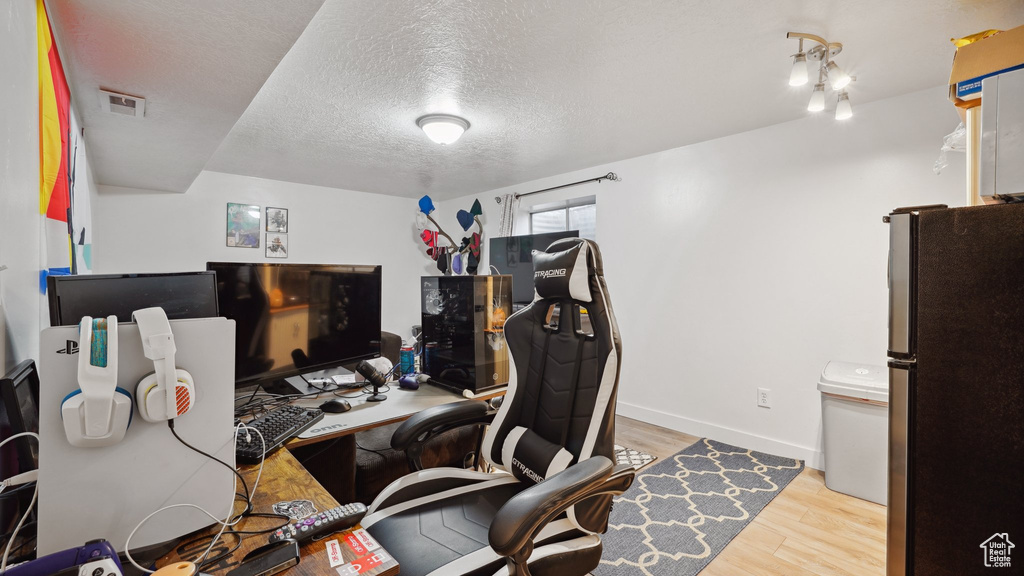 Office space featuring visible vents, a textured ceiling, baseboards, and wood finished floors