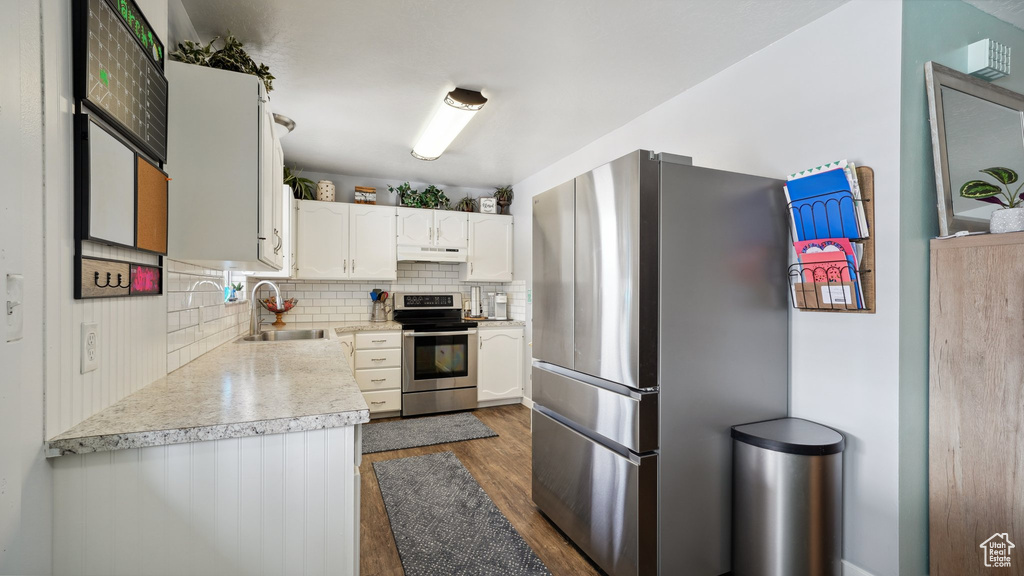 Kitchen featuring dark wood-style flooring, a sink, decorative backsplash, light countertops, and stainless steel appliances