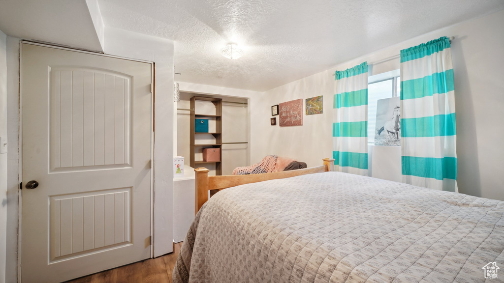 Bedroom with a textured ceiling and wood finished floors