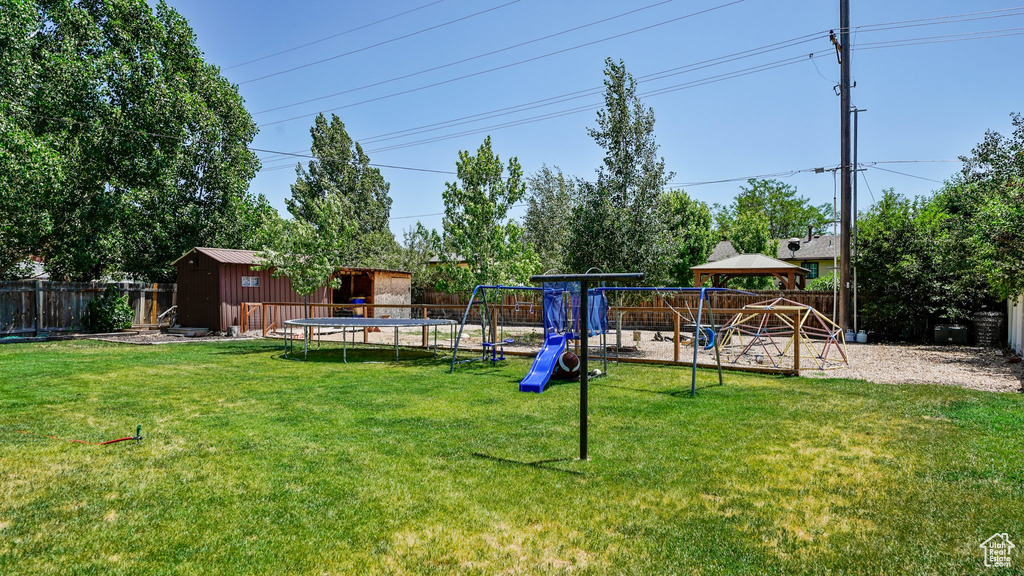 Fenced backyard featuring a playground, a shed, and a gazebo