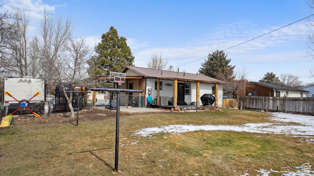 Back of property featuring fence private yard, cooling unit, metal roof, a yard, and a patio