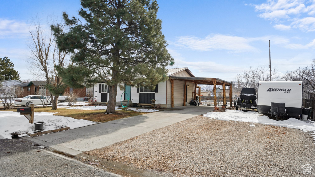 View of front of home with an attached carport, driveway, and metal roof