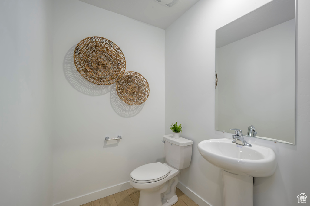Bathroom featuring baseboards, toilet, and wood finished floors
