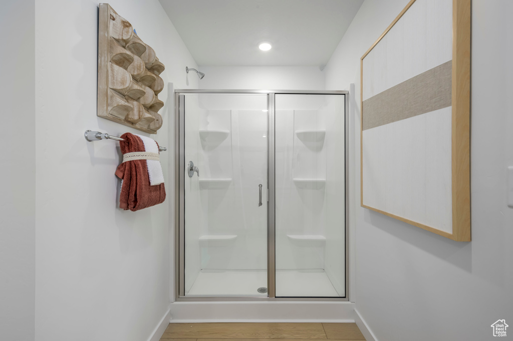 Bathroom with baseboards, wood finished floors, and a shower stall