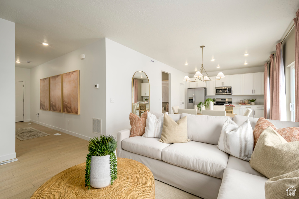 Living area featuring visible vents, baseboards, recessed lighting, light wood-style floors, and a notable chandelier