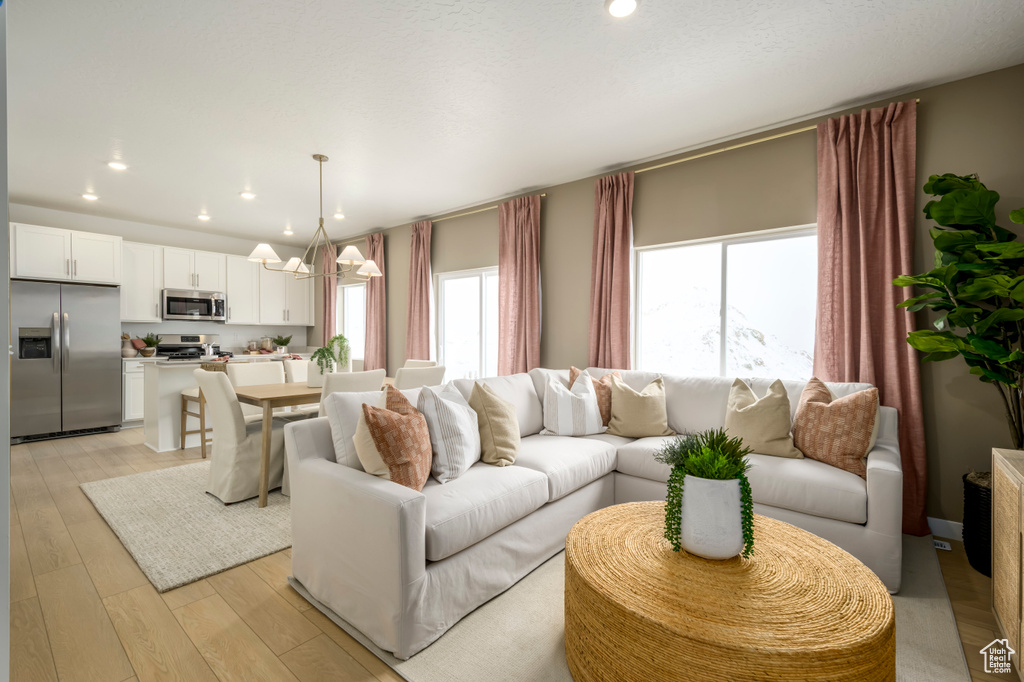 Living room with light wood finished floors, recessed lighting, and an inviting chandelier