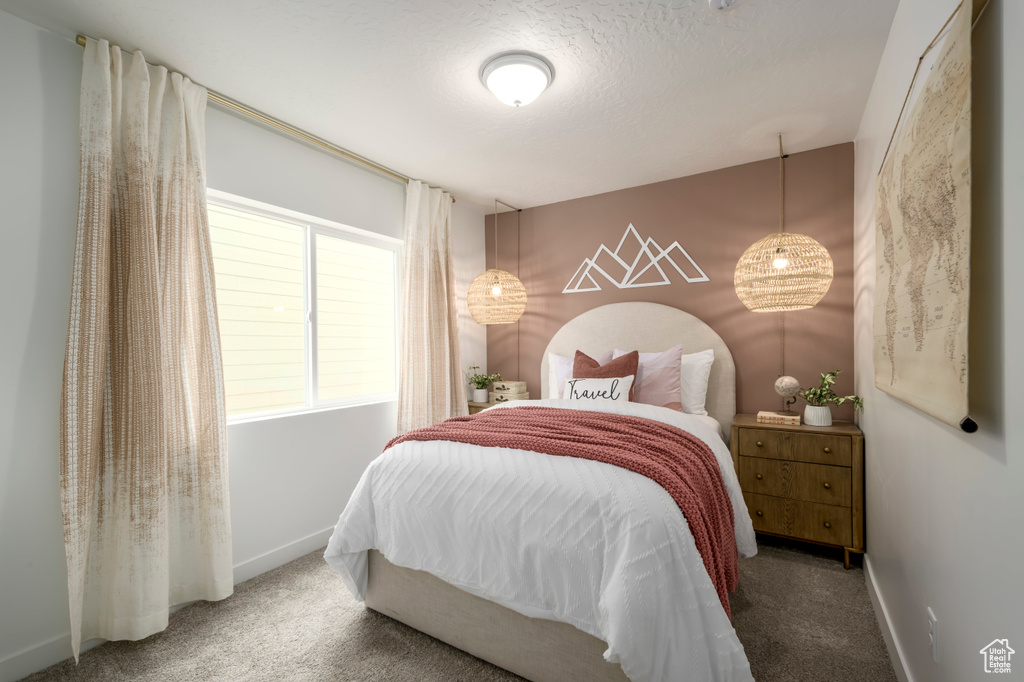 Carpeted bedroom featuring baseboards and a textured ceiling