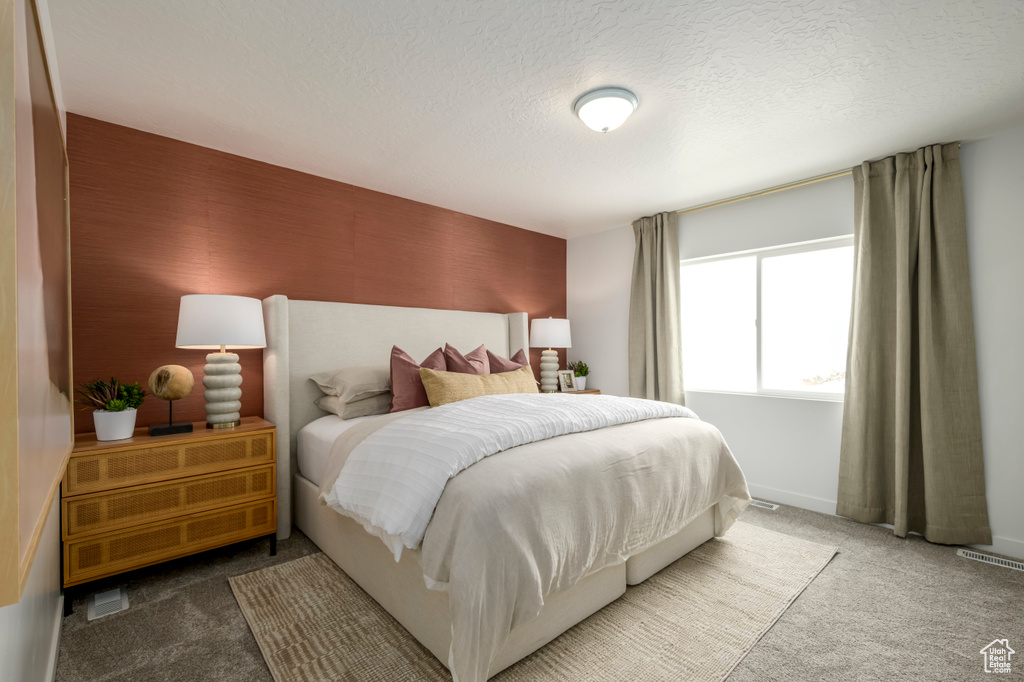Bedroom with visible vents, baseboards, a textured ceiling, and carpet flooring
