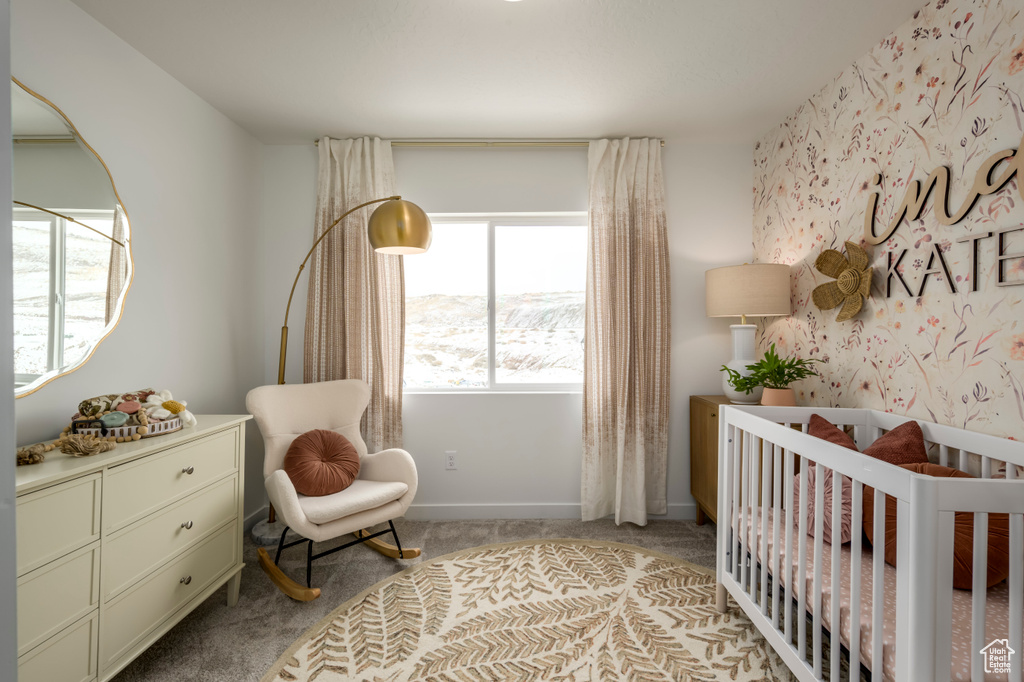 Bedroom with baseboards, wallpapered walls, a crib, and carpet