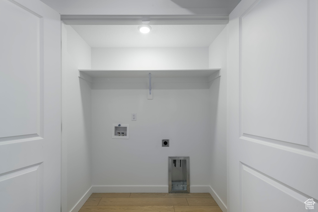 Clothes washing area featuring light wood finished floors, hookup for an electric dryer, baseboards, and washer hookup