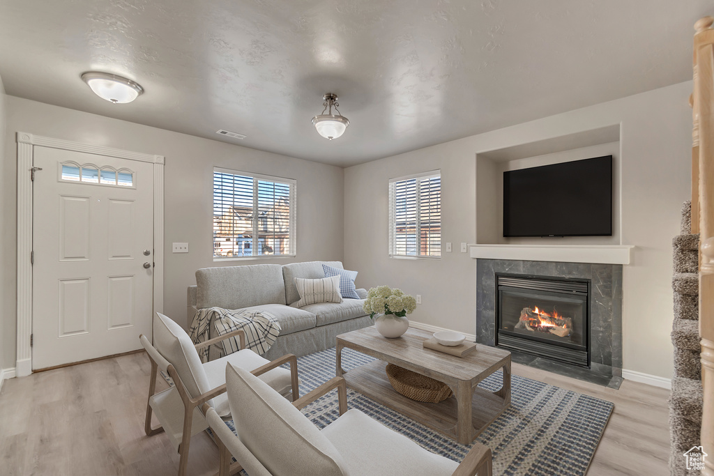 Living area featuring light wood finished floors, visible vents, a fireplace, and baseboards