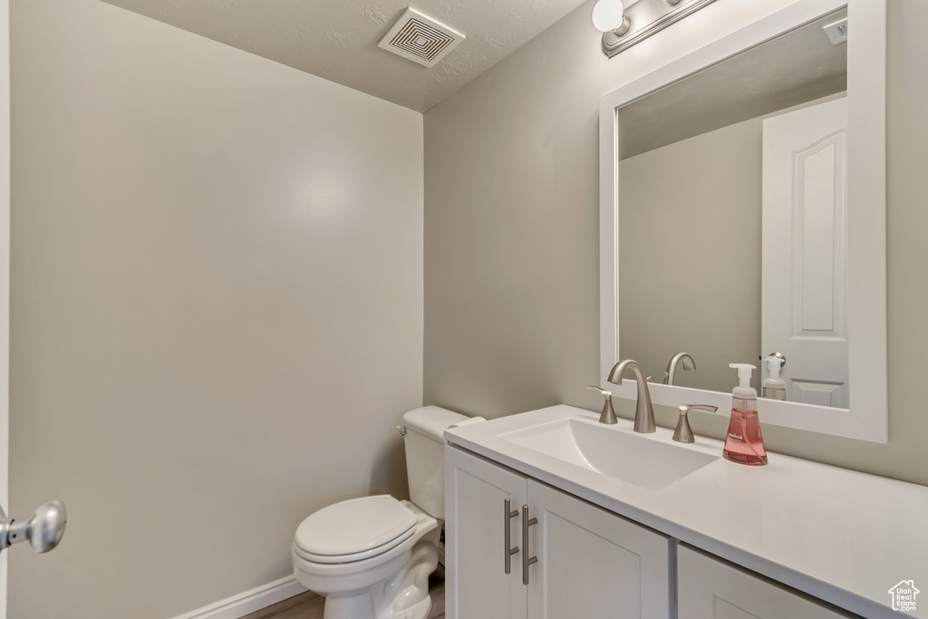 Bathroom featuring visible vents, toilet, vanity, and baseboards