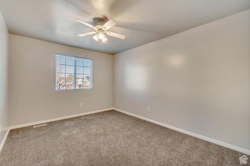 Carpeted spare room with visible vents, baseboards, and a ceiling fan